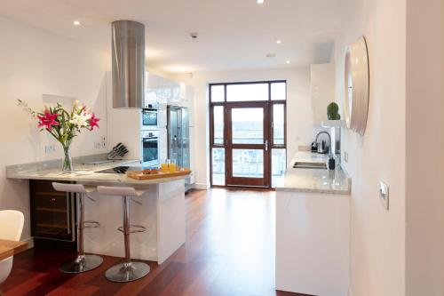une cuisine avec des murs blancs et un comptoir orné de fleurs. dans l'établissement Hampden Apartments - The Henry, à Windsor