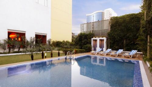 a pool with lounge chairs next to a building at Lemon Tree Hotel Chennai in Chennai