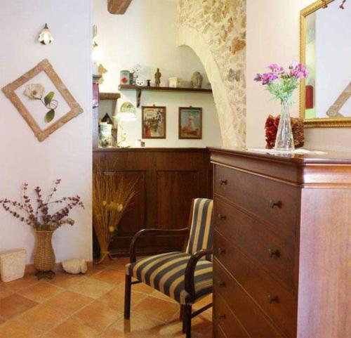 Cette chambre comprend une chaise et une commode avec un miroir. dans l'établissement Italiana Resort Magnolia, à Syracuse