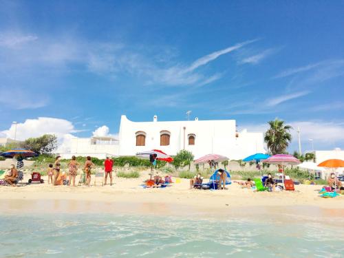 a group of people on a beach with a white building at Villa Layla on the beach in Torre Lapillo
