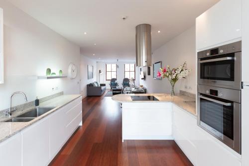 a kitchen with white cabinets and a living room at Hampden Apartments - The Charles in Windsor