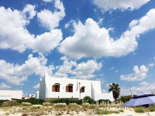 a white building on the beach with a cloudy sky at Villa Layla on the beach in Torre Lapillo