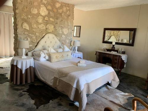 1 dormitorio con cama y pared de piedra en Tarentaal Guest Farm, en Outjo