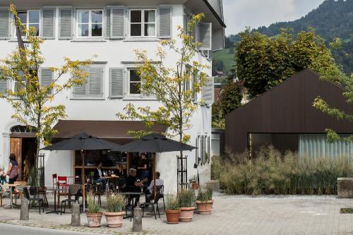 a restaurant with tables and umbrellas in front of a building at BAR10ZIMMER in Dornbirn