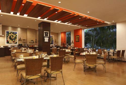 restauracja ze stołami i krzesłami w pokoju w obiekcie Lemon Tree Hotel Chennai w mieście Ćennaj