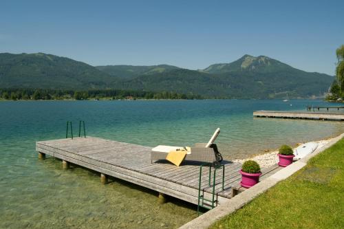 a dock on a lake with a table and a chair at Hotel Garni Buchinger in St. Wolfgang