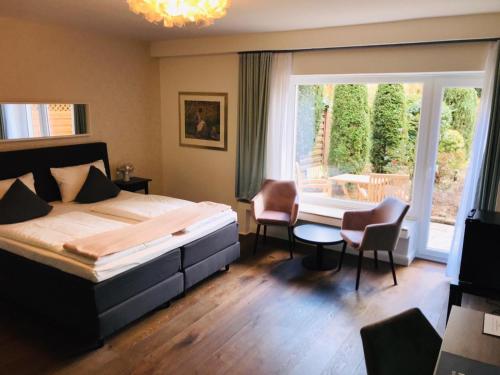 a bedroom with a bed and chairs and a window at Monopol Boutique Hotel in Bremen