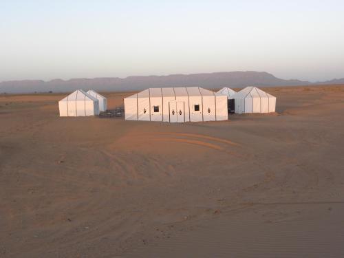 a group of white buildings in the desert at Sahara Luxury Camp in Zagora