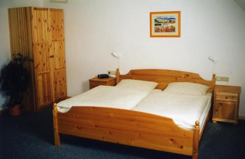 a bedroom with a wooden bed with white sheets at Pension Am Thieberg in Landolfshausen