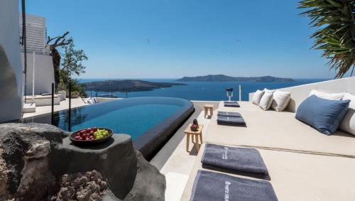 a villa with a pool and a view of the water at Porto Fira Suites in Fira