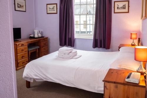 a bedroom with a bed with a phone and a desk at The Crown Hotel in Alton