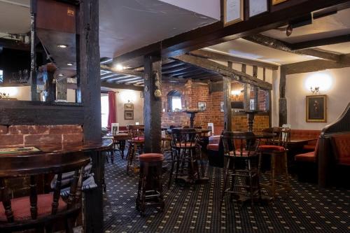 um bar com bancos e mesas de madeira num pub em The Crown Hotel em Alton
