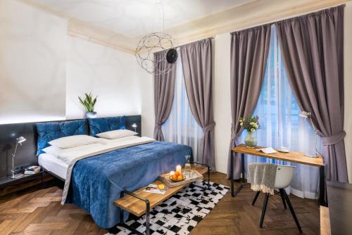 a bedroom with a blue bed and a table at MOOo by the Castle in Prague