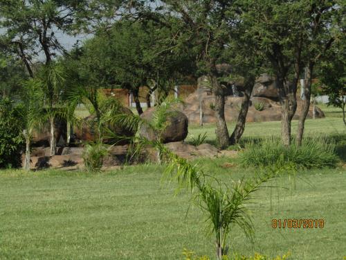a field of grass with trees and rocks at Vido Lodge and Conference Centre in Polokwane