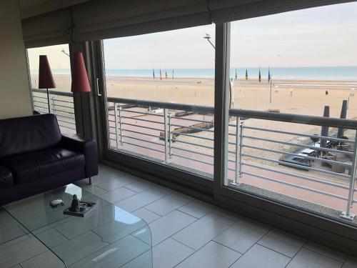 a living room with a couch and a view of a beach at Residentie Albert-1, app.202, Zeelaan 214 in De Panne