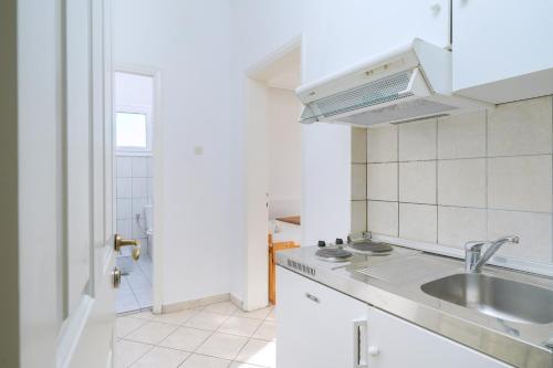 a white kitchen with a sink and a microwave at Villa Margarita in Limenaria