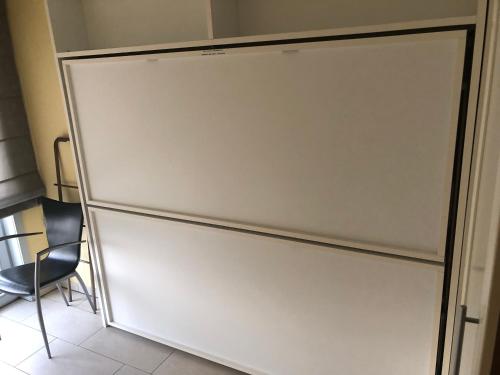 a white refrigerator in a room with a chair at Residentie Albert-1, app.202, Zeelaan 214 in De Panne