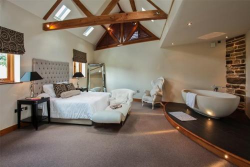 een grote slaapkamer met een bed en een bad bij Whytings Stud Barn 1 in Horsham