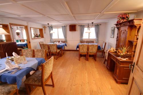 ein Esszimmer mit Tischen und Stühlen und Fenstern in der Unterkunft Hotel Adler Garni in Hirschegg