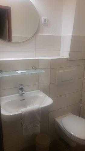a white bathroom with a sink and a toilet at Pension am Stern in Leipzig