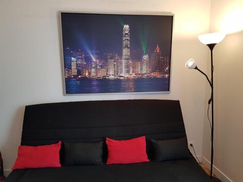 a living room with a black couch with red pillows at Appartement avec rez de jardin à Disneyland in Montévrain