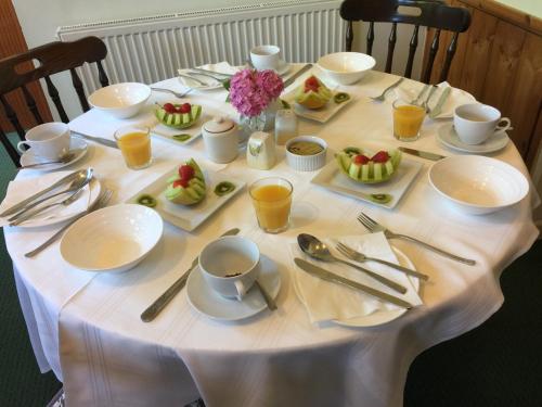 una mesa con platos, utensilios y fruta. en Parkfield (Chepstow BnB), en Chepstow