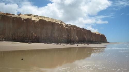 a large cliff next to a beach with water at Castelo Cabo de Sao Roque in Maxaranguape