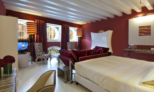 a bedroom with a bed and chairs and a tv at Sina Centurion Palace in Venice