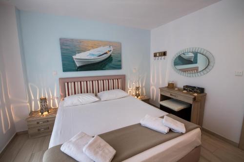 Ilianthos Apartments & Rooms في ميكروس جيالوس: غرفة نوم بسرير ابيض كبير ومرآة