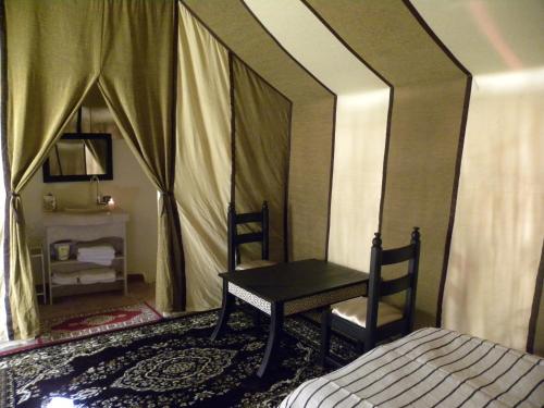 a bedroom with a bed and a table and chair at Sahara Luxury Camp in Zagora
