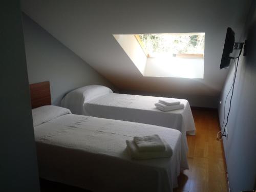 a attic room with two beds and a window at Apartamento Good Way in O Pedrouzo