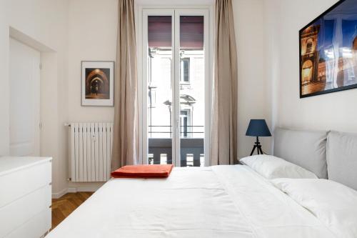 a white bedroom with a white bed and a window at Appartamento dietro Fontana del Nettuno in Bologna