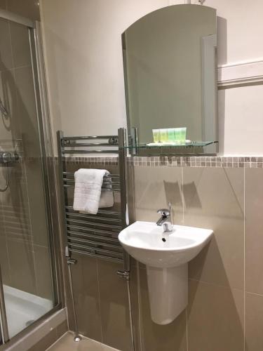 uma casa de banho com um lavatório e um chuveiro com um espelho. em Lanark Residence em Edinburgo