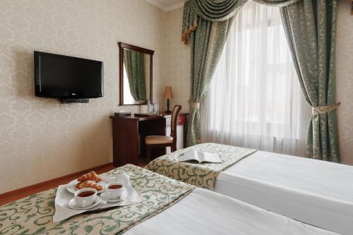 a hotel room with two beds and a tv at Royal Street Hotel in Odesa