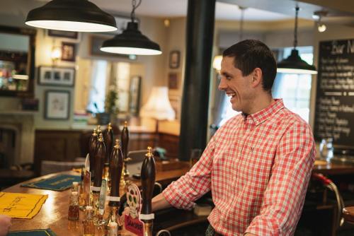a man standing behind a bar in a pub at The Highdown – Brunning and Price in Worthing