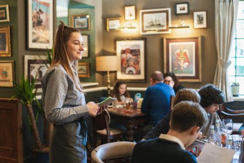 a woman standing in a restaurant holding a cell phone at The Highdown – Brunning and Price in Worthing
