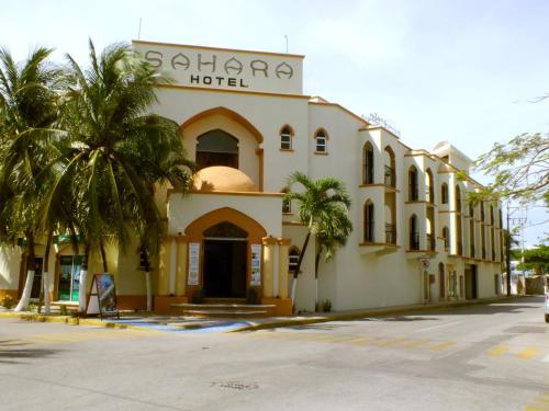 a hotel with palm trees in front of it at Gran SAHARA in Playa del Carmen
