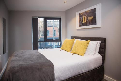 Un dormitorio con una cama con almohadas amarillas y una ventana en Dream Apartments St Thomas Hall, en Belfast