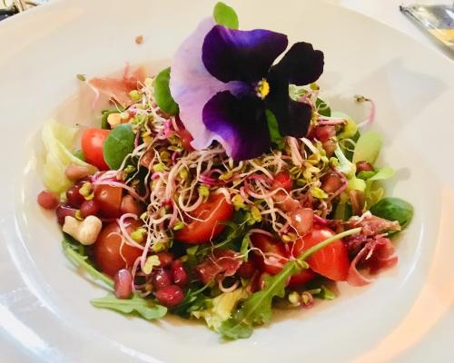 a salad with a purple flower on a white plate at Neptun in Międzychód