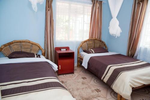 two beds in a room with blue walls and a window at Mutheto Lodge in Lilongwe