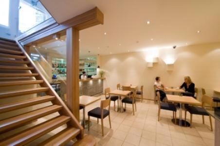 a restaurant with two people sitting at tables and a staircase at Hotel Homeland in Tampere