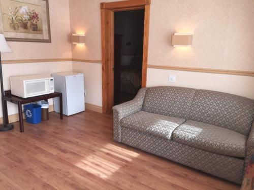 a living room with a couch and a microwave at Hotel Motel La Marquise in Sherbrooke
