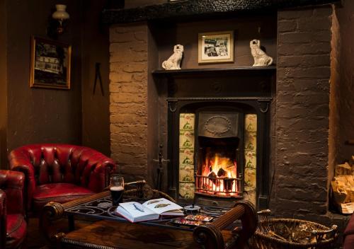 a living room with a fireplace and a red chair at Brown Trout Golf & Country Inn in Aghadowey