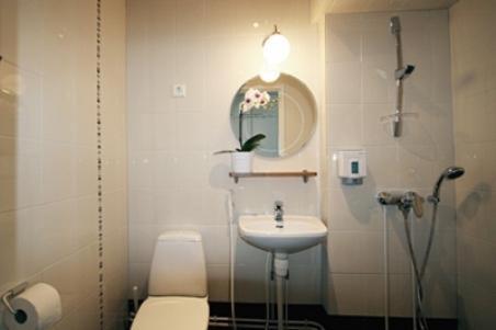 a bathroom with a sink and a toilet and a mirror at Hotel Homeland in Tampere