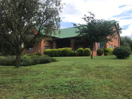 a brick house with a green roof at Olive Tree Farm in Magaliesburg