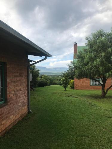 a brick building with a tree in a yard at Olive Tree Farm in Magaliesburg