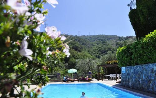a person in a swimming pool with a mountain in the background at Borgo San Francesco in Gioiosa Marea