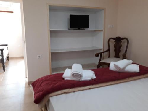 a bedroom with a red bed with a chair and a television at MARIA GUESTHOUSE KINI in Kinion