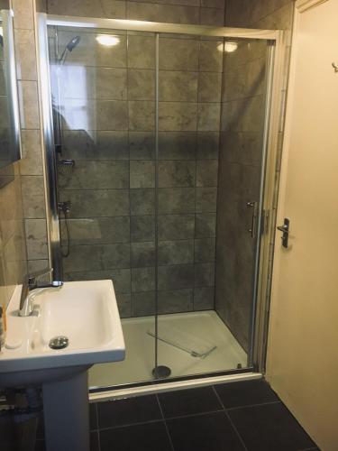 a shower with a glass door next to a sink at Normanton Park Hotel, Sure Hotel Collection by Best Western in Oakham