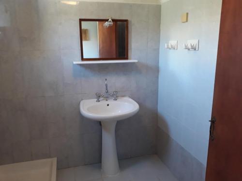 a bathroom with a white sink and a mirror at MARIA GUESTHOUSE KINI in Kinion